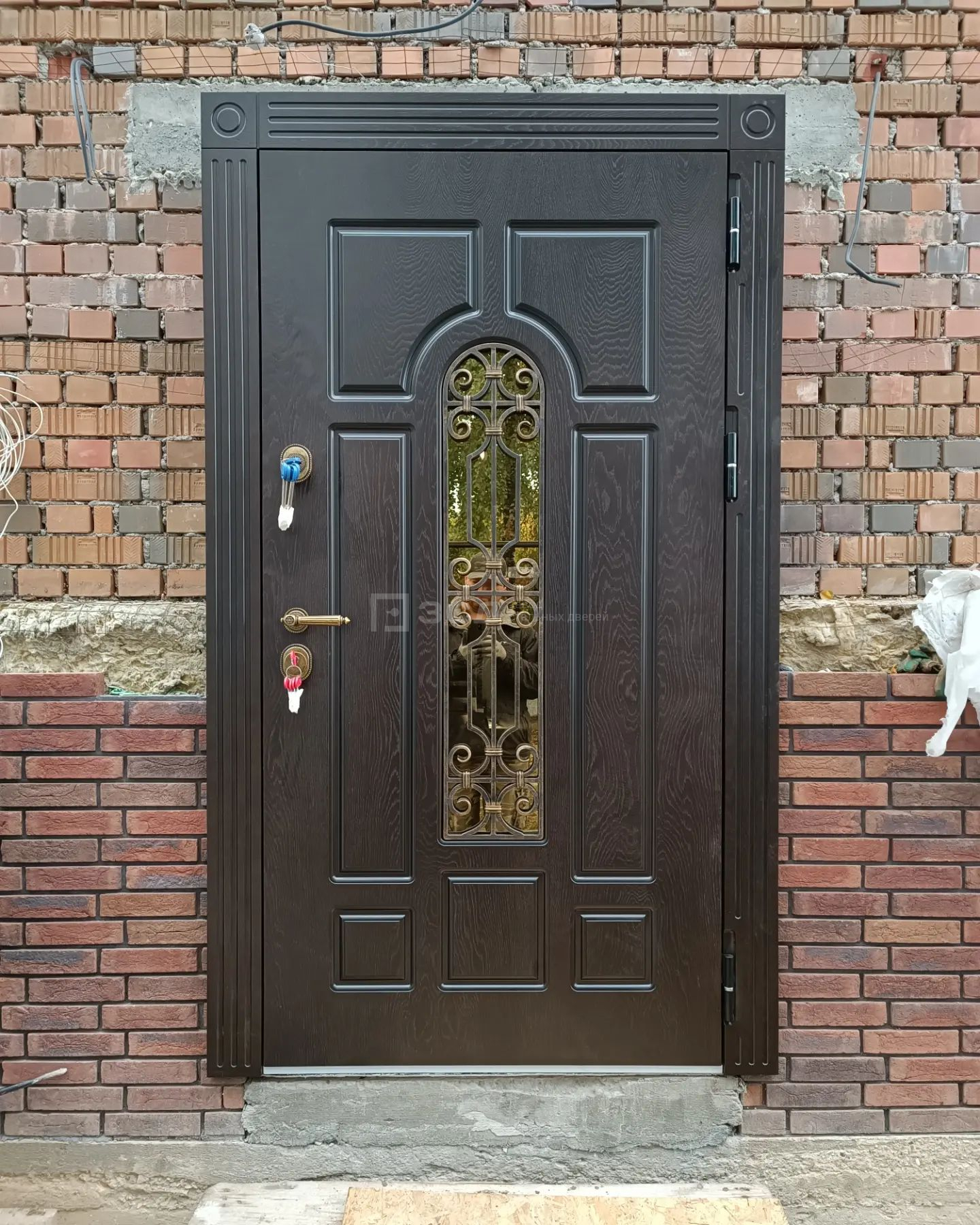 Входная дверь со стеклом и ковкой коричневого цвета